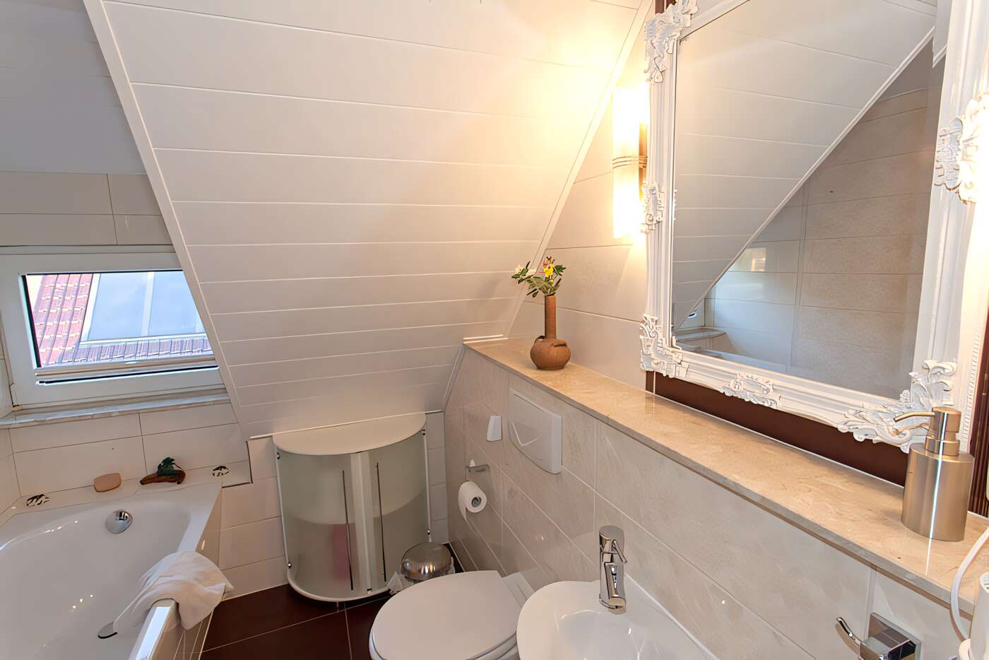 Das kleine Bad des Ferienhauses mit Badewanne, Waschplatz und WC im Dachgeschoss